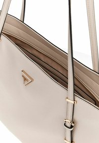 Borsa a spalla in pelle di un morbido beige con dettagli neri, dotata di chiusura a zip superiore, hardware dorato e una tasca interna.
