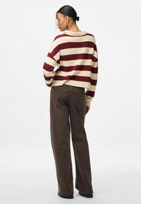 Svītrains džemperis krēmkrāsā un bordo, īss modelis; kombinēts ar platām brūnām biksēm ar aizmugurējām kabatām. Gluda tekstūra un relaksēts siluets.