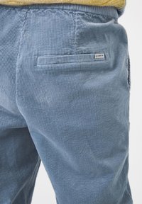 Vue arrière d'un pantalon en corduroy bleu clair avec une petite étiquette rectangulaire de la marque Garcia sur la poche arrière droite.