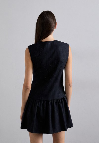 Rochie neagră fără mâneci, cu un corset ajustat, model cu dungi fine și o fustă evazată cu volane. Material moale și texturat, cu detalii subtile.