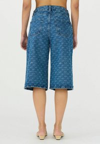 Denim culotte kratke hlače v srednje modri barvi, z visokim pasom, širokimi nogavicami in zadnjimi žepi. Obrežene malo pod kolenom.