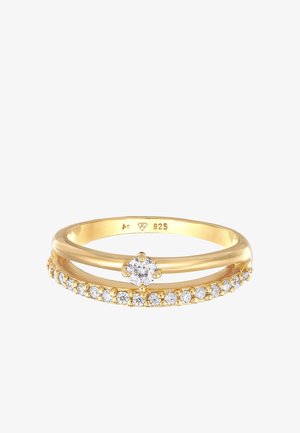 Guldfarvet ring med en central rund sten og en ringforbindelse prydet med mindre klare sten, fremstillet af 925 sterling sølv.
