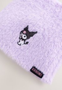 Borsetta soffice color lavanda con il personaggio Kuromi ricamato. Presenta una texture morbida e un'etichetta nera con la scritta "KUROMI" in lettere rosa.