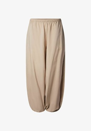 Beige bukser med løs passform, elastisk midjebånd og elastiske ankelmansjetter, laget av lett stoff.