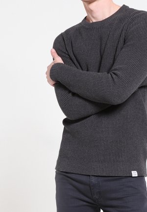 Pull en tricot côtelé gris foncé, à manches longues, col rond et tissu texturé ; petite étiquette dans le coin inférieur gauche de l'ourlet.