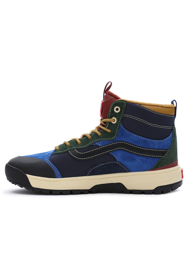 Zapatilla de bota alta con una mezcla de materiales en azul, verde, rojo y marino. Presenta una puntera de goma, acentos texturizados y cordones en color marrón. Suela ligera.