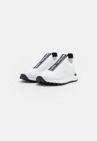 White knit sneakers with black accents and logo, slip-on design, textured upper, and black rubber sole for grip and durability.