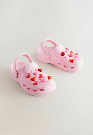Rosa Clogs aus leichtem Material mit herzförmigen Verzierungen in verschiedenen Farbtönen, Belüftungslöchern und einem Fersenriemen.