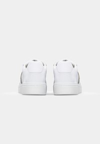 Sneaker bianco con tomaia in pelle liscia, punta rotonda, colletto imbottito e suola in gomma piatta. Presenta dettagli del logo sul lato.