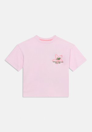 T-shirt cropped rosa chiaro con maniche corte, una piccola grafica di un fiore e testo nella parte superiore sinistra del petto.