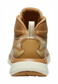 Brauner Sportschuh mit einem strukturierten Stoff-Obermaterial, gepolstertem Kragen und einer weißen Sohle. Verfügt über eine Zuglasche an der Ferse für ein einfaches Anziehen.