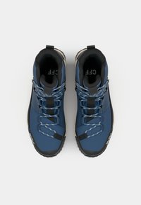 Zilas pārgājienu zābaki no sintētiskā materiāla ar melnām gumijas zolēm. Aprīkoti ar pelēkām šņorēm, melnām detaļām un aizmugurējo cilpu ērtai uzvilkšanai.