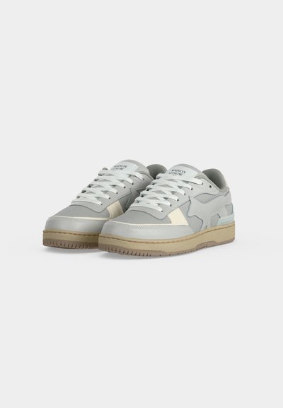 Ζευγάρι χαμηλά sneakers σε ανοιχτό γκρι και μπεζ με άσπρα κορδόνια, μπεζ σόλες και διακόσμηση σε σχήμα αστεριού στο πλάι, σε μονόχρωμο φόντο.