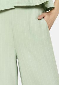 Svetlozelene, prugaste hlače iz blaga gladke teksture. Imajo stranske žepe in udoben kroj, primerne za sproščeno nošenje.