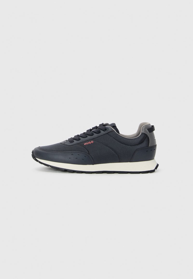 Navy blue sneakers with a smooth synthetic upper, rounded toe, gray accents, lace-up design, and a white midsole with a textured black outsole.