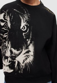 Černá mikina s velkým, detailním grafikou tygří tváře v bílé barvě, s žebrovaným výstřihem a manžetami.