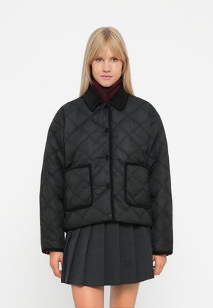 Veste noire matelassée avec un col rond, fermeture à boutons sur le devant et deux poches plaquées, se distinguant par un contour contrastant le long des bords.