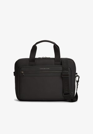 Melna klēpjdatora soma no gludas materiāla ar rāvējslēdzēja priekšpuses kabatu, divām rokturiem un regulējamu plecu siksnu ar zīmola nosaukumu.