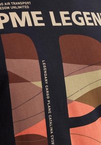 Tamnoplavi pamučni majica s grafičkim dizajnom koji sadrži apstraktne oblike u smeđoj, ružičastoj i bež boji. Uključeni su tekstovi: "PME LEGEND" i "LEGENDARY CARGO PLANE CATALINA CV28."