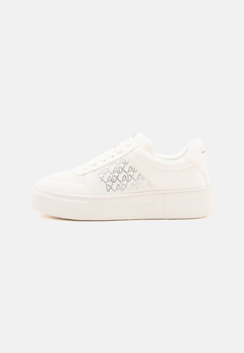 Λευκό sneaker πλατφόρμας με κορδόνια μπροστά, μοτίβο ρομβοειδών από στρας στο πλάι και παχιά σόλα σε απλό φόντο.