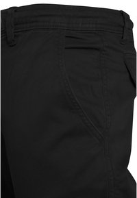 Pantalones negros hechos de tela tejida, con una textura suave, ajuste recto y un bolsillo lateral con detalles de costura limpia.