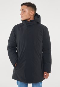 Parka nera impermeabile con cappuccio, dotata di chiusura frontale con zip, due tasche laterali e una texture liscia e imbottita.