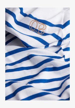 Baumwollstoff mit horizontalen weißen und blauen Streifen. Verfügt über ein kleines, goldgesticktes Logo, das auf dem Stoff platziert ist.