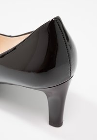 Chaussure à talon haut en cuir verni noir avec un bout pointu et une finition lisse. Présente un design élégant et un talon aiguille de hauteur modérée.