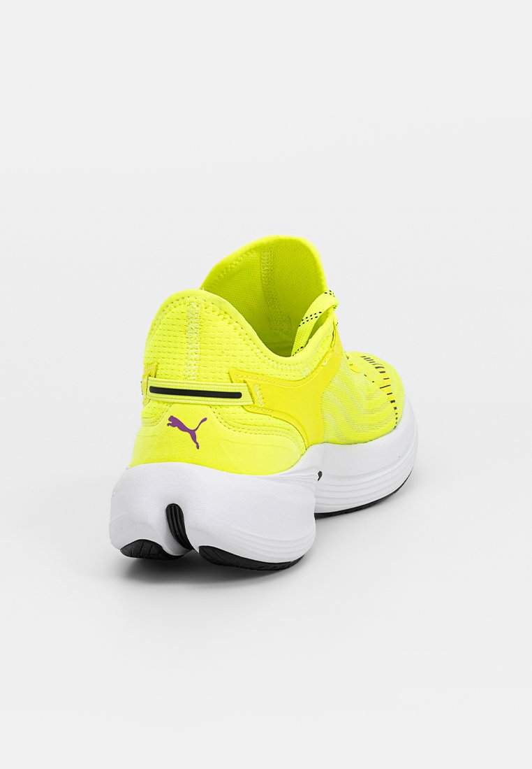 Neon żółte buty sportowe z teksturowaną cholewką, z purpurowym logo, oddychającą siateczką oraz białą podeszwą środkową z czarnymi akcentami.