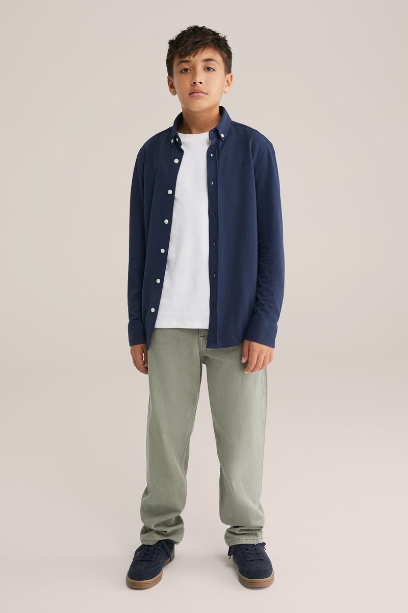 Námořnická košile s dlouhým rukávem, zapínání na knoflíky, přesažená přes bílý tričko, v kombinaci s světle zelenými džíny a námořnickými teniskami. Hladký materiál, volný střih.