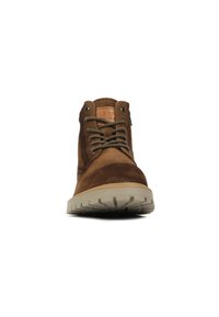 Stivaletti ankle in suede marrone con lacci piatti color beige, suola in gomma e patch in pelle con logo. Punta rotonda e colletto imbottito per il comfort.