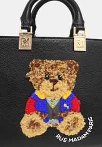 Borsa a mano in pelle nera con un ricamo di un orsetto colorato e strutturato, con accenti blu, rossi e gialli; accessori in oro sulle maniglie.