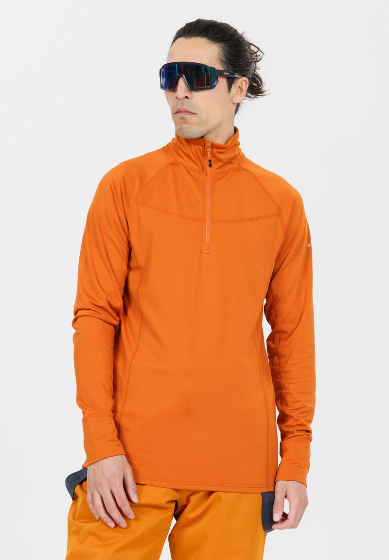 Oranger Langarm-Pullover mit einem Viertelreißverschluss, glatter Textur und taillierter Passform; kombiniert mit orangen Hosen und reflektierenden Sonnenbrillen.