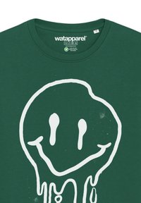 Groen katoen T-shirt met een groot wit smiley-gezicht ontwerp met druppelaccenten. Ronde halslijn en label zichtbaar aan de binnenkant.