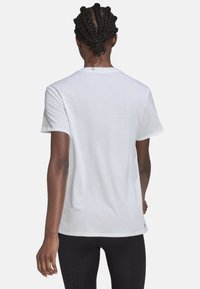 Camiseta blanca de manga corta que presenta una textura suave, cuello redondo y un ajuste relajado. Incluye un sutil logo de la marca en el dobladillo.
