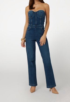 Kombinezon z dżinsu z dekoltem w serce, dopasowaną górą i szerokimi nogawkami. Kolor ciemnoniebieski z delikatną fakturą i przednimi kieszeniami.
