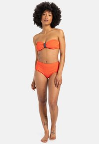 Oranžový rebrovaný bikiny set obsahuje top bez ramienok s šedým kovovým akcentom a vysoké nohavičky. Hladká textúra a priliehavý dizajn.
