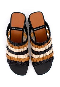 Sandalias de slide trenzadas en negro, marrón, crema y tostado, con rayas horizontales y una suela plana con una plantilla suave en tono tostado.