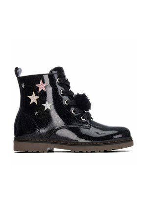 Botín negro brillante para niña con parches de estrellas, cordones negros con detalle de pompón y suela marrón acanalada.