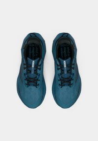 Paru plavih New Balance Nitrel trail trkačkih cipela s crnim vezicama, mrežastim gornjim dijelom i podstavljenim okovratnicima na bijeloj pozadini.