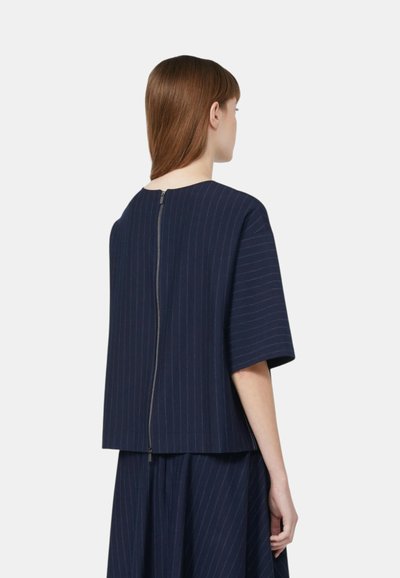 Top a righe navy con maniche corte e chiusura con zip sulla parte posteriore. Realizzato in tessuto texturizzato, presenta una silhouette ampia.