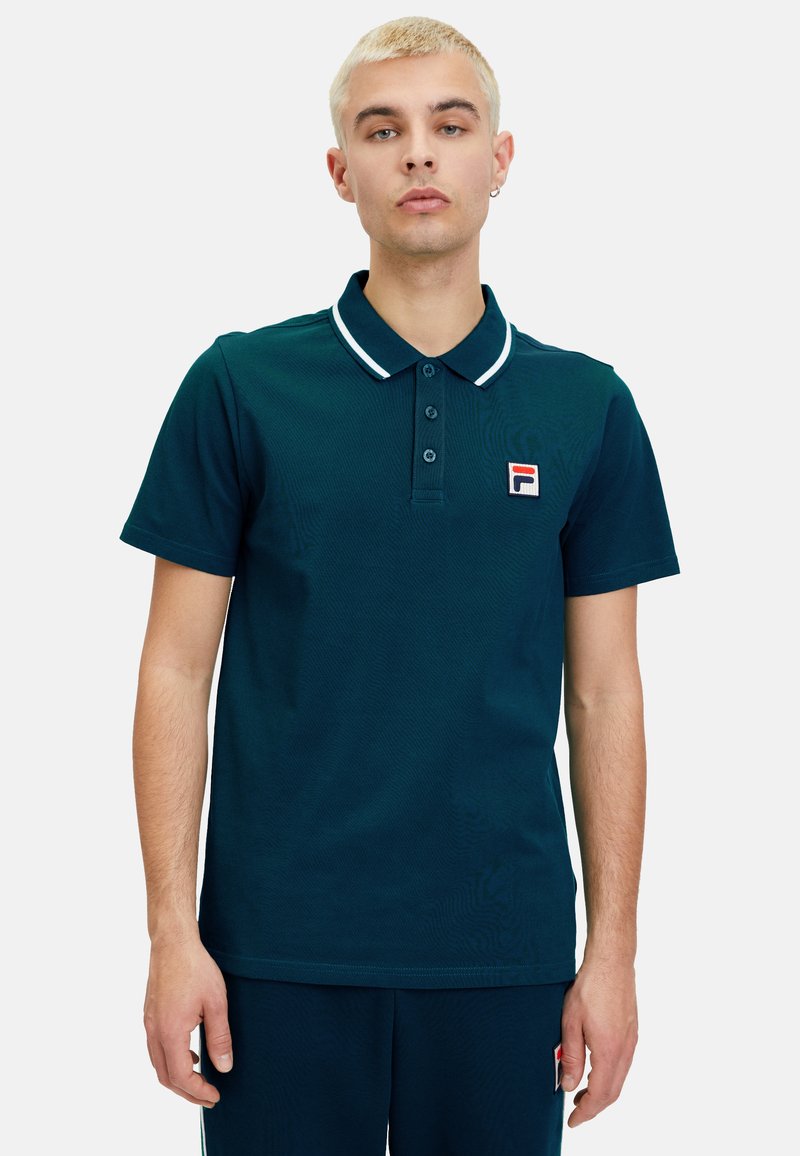 Polo shirt verde scuro realizzato in tessuto texturizzato, con una patta a tre bottoni, colletto bianco a contrasto e una piccola etichetta con logo sul petto.