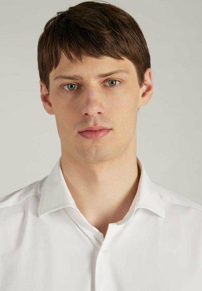 Camicia bianca con colletto a punta, texture liscia e un leggero lucido. Il modello ha capelli corti castani e un tono di pelle neutro.