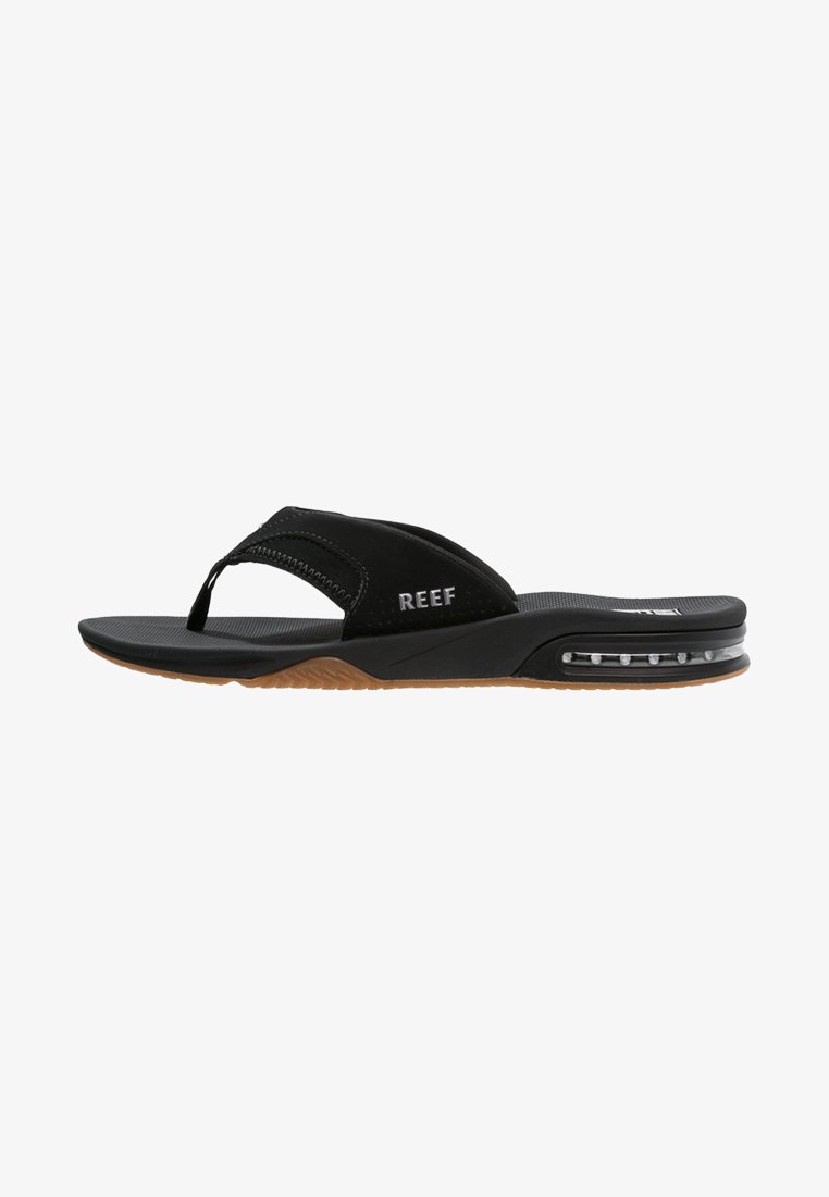 Chinelo preto com uma tira macia, palmilha texturizada e sola de borracha com um compartimento de ar visível. Logótipo da marca visível na tira.