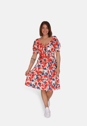 Robe florale avec des manches courtes bouffantes, dans des couleurs rouge, bleu et blanc. Elle présente un lien à l'avant et une silhouette en A jusqu'au genou.