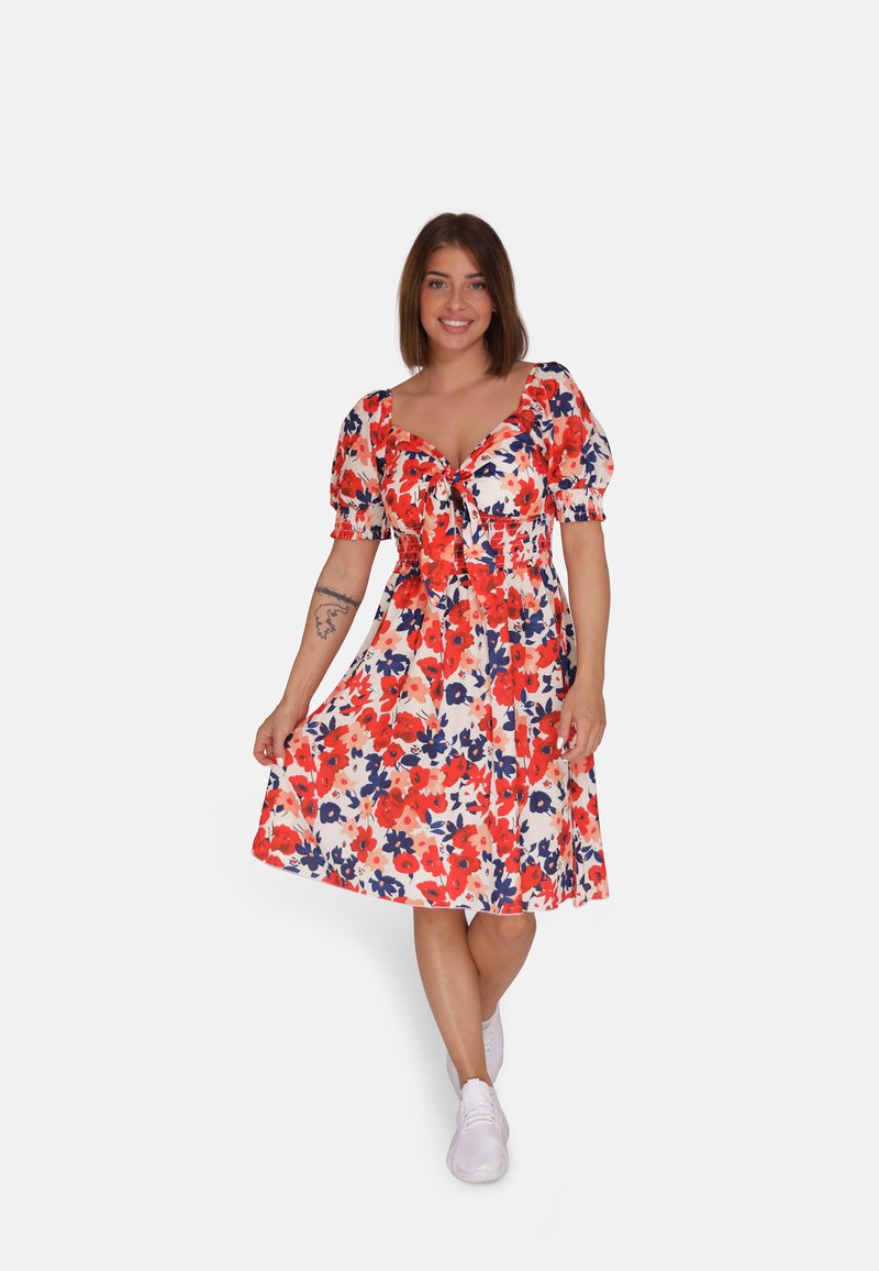 Bloemenjurk met korte pofmouwen, in de kleuren rood, blauw en wit. Heeft een strik aan de voorkant en een knielange, A-lijn silhouet.