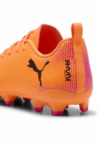 Πορτοκαλί γίνει παπούτσια ποδοσφαίρου για νέο�υς με λείο συνθετικό πάνω μέρος, ροζ διαβαθμισμένο σχέδιο, μαύρο λογότυπο και μορφοποιημένα καρφιά για πρόσφυση.