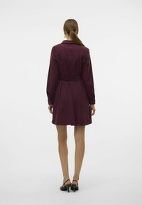 Robe bourgogne à manches longues avec une taille ceinturée et un col de chemise. Tissu lisse avec une coupe au genou et des poignets boutonnés.
