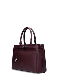 Burgundy textured leather handbag with double handles, silver-toned clasp, and decorative hanging charm against white background.
