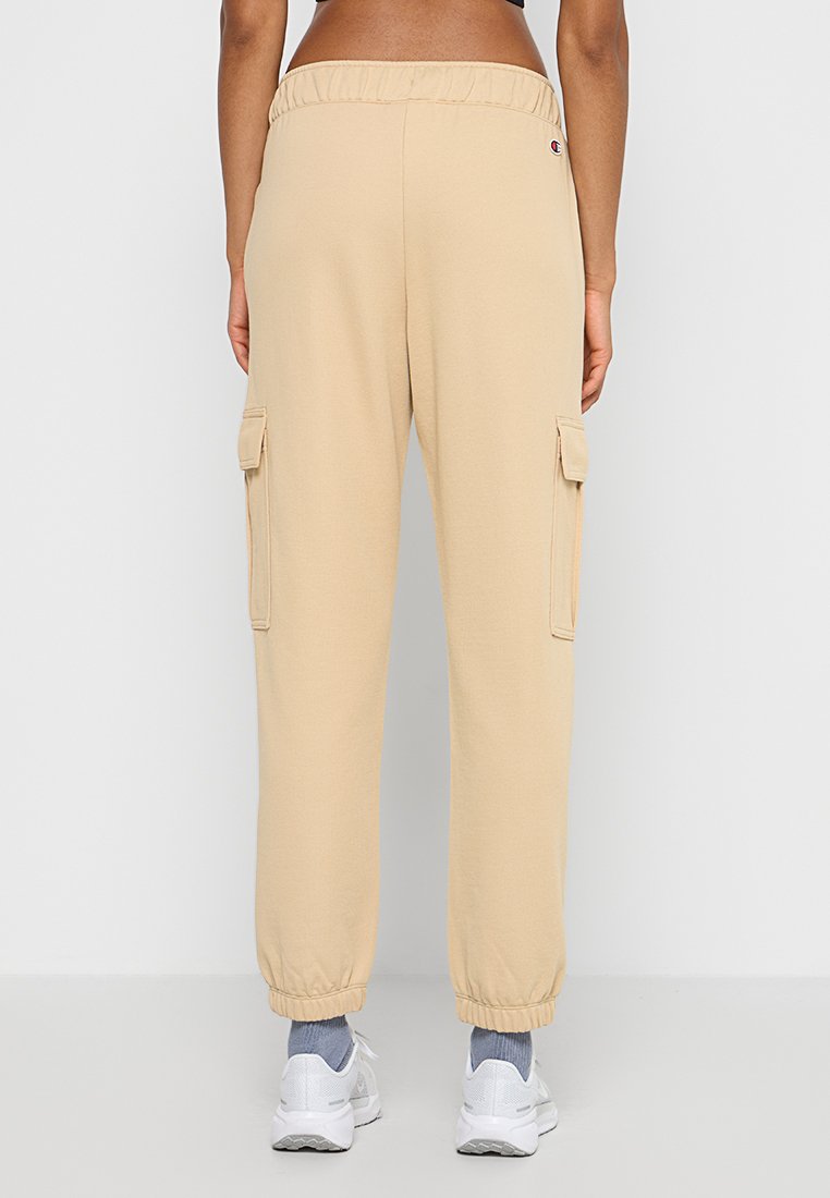 Joggers cargo beiges avec une taille élastique, des poches latérales et des poignets élastiques aux chevilles, fabriqués en tissu doux et texturé.